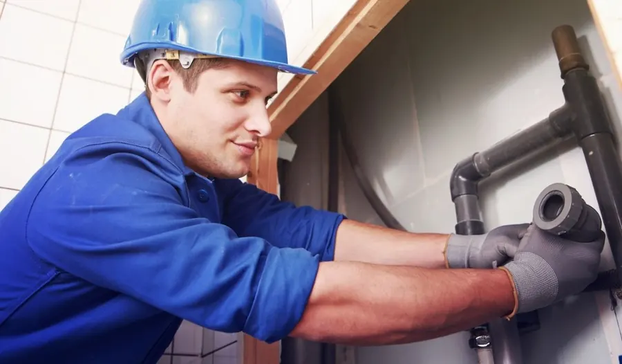 Close-up of plumber tightening copper pipe fittings near water heater